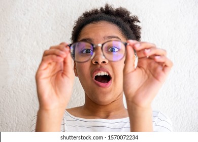 Close up portrait of young african american girl holding glasses making funny face