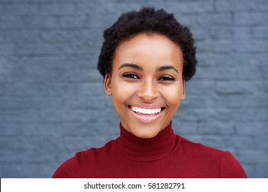 Close up portrait of young african woman smiling against gray wall - Powered by Shutterstock