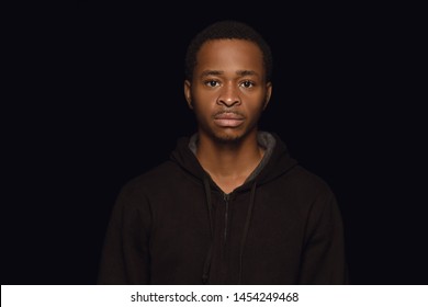 Close Up Portrait Of Young African-american Man Isolated On Black Studio Background. Real Emotions Of Male Model. Standing And Looks Serious. Facial Expression, Human Nature And Emotions Concept.