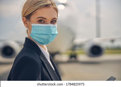 Close Up Portrait Of A Young Airline Employee In A Face Mask Posing For The Camera