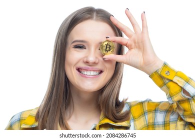 Close up portrait of a young amused smiling female holding bitcoins in front of her eyes. Concept of a bright future, wealth, innovation, investment