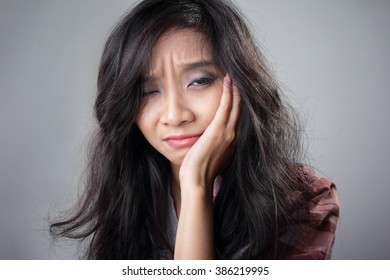 Close Up Portrait Of Young Asian Woman Expressing Pain Of Having A Toothache, Over Grey Background