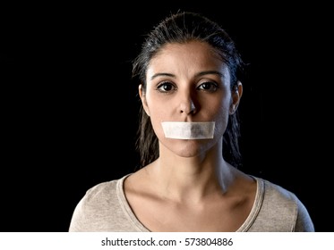 close up portrait of young attractive woman with mouth and lips sealed in adhesive tape restrained and abused censored and banned to speak and express opinion in freedom concept - Shutterstock ID 573804886
