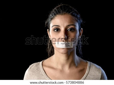 close up portrait of young attractive woman with mouth and lips sealed in adhesive tape restrained and abused censored and banned to speak and express opinion in freedom concept