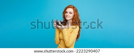 Close up Portrait young beautiful attractive ginger girl happy smiling with vintage camera and ready to travel. Blue Pastel Background. Copy space