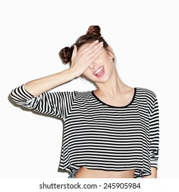 Close Up Portrait Of Young Beautiful Girl Having Fun And Hiding Her Face With Hand. Natural Makeup And Top Knot Hairdo. White Background, Not Isolated. Inside.