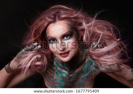close up  portrait of young beautiful girl with colorful face painting. professional makeup. hair in paint. beauty portrait. pink flying hair
