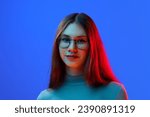 Close up portrait of young beautiful lad, teenager looking at camera against blue background in mixed neon light, filter. Concept of beauty, human emotions, facial expression, fashion and style. Ad