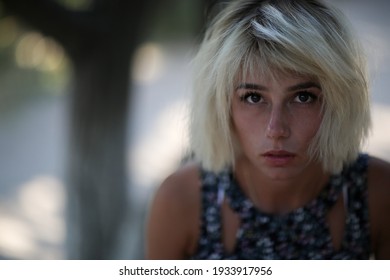 a close up portrait of a young beautiful tanned thin girl with white short hair and dark brown eyes without retouching