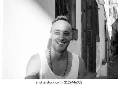 Close Up Portrait Of A Young Blonde Man Smiling Against A Wall In Italy