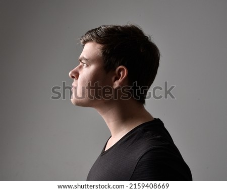 close up portrait of young brunette man in profile with silhouette rim lighting on studio background with a variety of canal expressions.