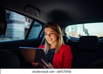 Close up portrait of a young business woman using digital tablet in the back seat of the car. - Powered by Shutterstock