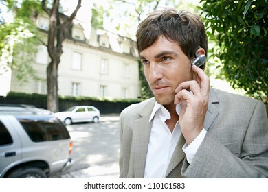 Close Up Portrait Of A Young Businessman Using An Ear Piece Microphone To Make A Phone Call.