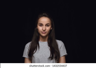 Close up portrait of young caucasian woman isolated on black studio background. Photoshot of real emotions of female model. Standing and looks serious. Facial expression, human nature and emotions