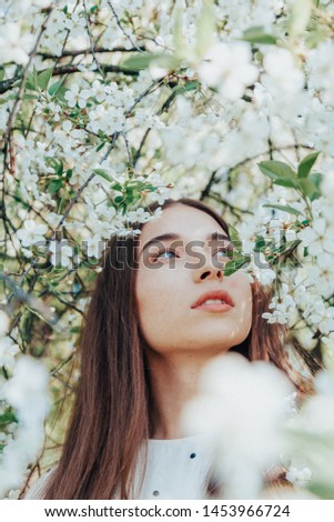 Close up portrait of young charming girl surrounded by cherry tree