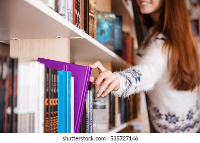 Close Up Portrait Of A Young Female Student Taking Book From Book Shelf