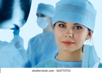 Close Up Portrait Of Young Female Surgeon Doctor Surrounded By Her Team. Group Of Surgeon In Operation Theatre. Healthcare, Medical Education, Emergency Medical Service And Surgery Concept