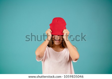 close up portrait of young funny female hiding under her red knitted cap. play the ass. play the ape