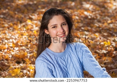 Close up portrait of a young girl in blue sweater, autumn park outdoor