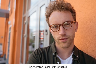 Close up portrait of young handsome business man wearing stylish eyeglasses standing on the street. Serious confident student looking at camera, education concept  - Powered by Shutterstock