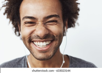 Close up portrait of young happy african man smiling listening to upbeat streaming music laughing over white background. Youth concept. - Shutterstock ID 633023144