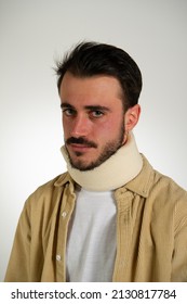 Close Up Portrait Of A Young Man Wearing A Beige Neck Protector. Neck Support For Safety With White Gray Background Isolated