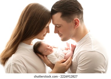 Close up portrait of young parents and newborn baby. Father and mother kiss and hug a beautiful newborn daughter. The concept of love, happy fatherhood and motherhood. Photography on white background.