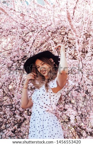 Close up portrait of young pretty lady with sakura flowers, in hat and with glasses