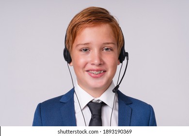 Close Up Portrait Of Young Schoolboy With Ginger Hair And Braces Wearing Dispatcher`s Headset Isolated Over Grey Background