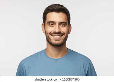Close up portrait of young smiling handsome guy in blue t-shirt isolated on gray background - Shutterstock ID 1180874596