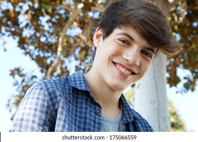 Close Up Portrait Of A Young Student Teenager Boy Near A Tree, Smiling Joyfully At The Camera During A Sunny Day Out. Outdoors Lifestyle.