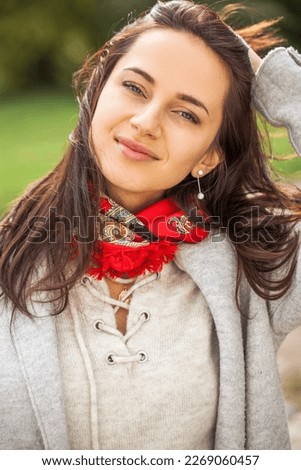 Close up portrait of a young stylish brunette woman in autumn park