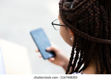 Close Up Portrait Of Young Woman With Braided Hair Wearing Eyeglasses Looking At Mobile Phone Screen Outside