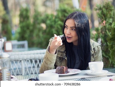 Close Up Portrait Of A Young Woman Eating Dessert Chocolate Ice Cream Licking Spoon Outdoors In Summer Terrace Coffee Shop. Side View