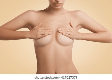Close up portrait of young woman with healthy clean skin covering naked breast with both hands.  Beautiful female having cosmetic procedure in beauty clinic. Aesthetic medicine and cosmetology concept