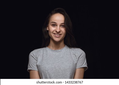 Close up portrait of young woman isolated on black studio background. Photoshot of real emotions of female model. Smiling, feeling happy. Facial expression, pure and clear human emotions concept.