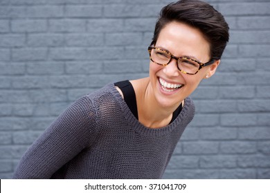 Close Up Portrait Of A Young Woman Laughing With Glasses Against Gray Background