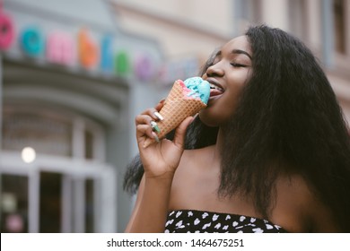 Close up portrait of a young woman licking ice cream outdoors in summer