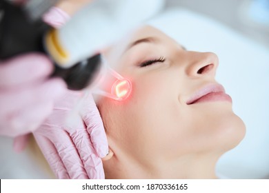 Close up portrait of a young woman patient receiving a laser treatment in a spa salon