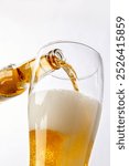 close up of pouring beer into a glass on white background.