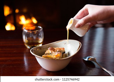 Close Up Of Pouring Custard Over Bread And Butter Pudding Dessert