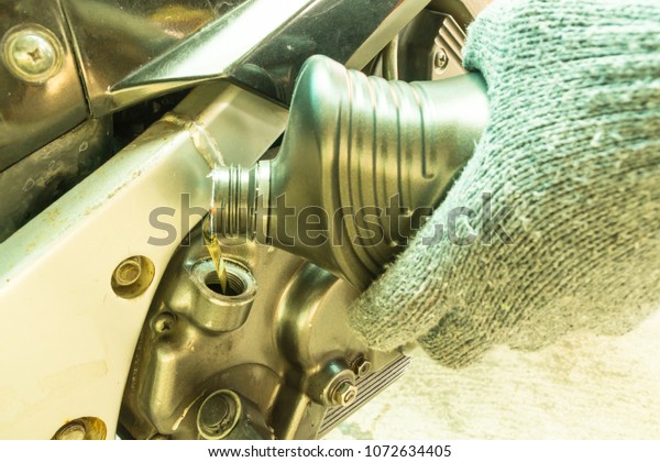 Close up of\
pouring new oil to motorcycle\
engine.
