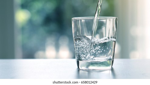 Cerca de verter agua potable purificada de la botella en la mesa en el salón