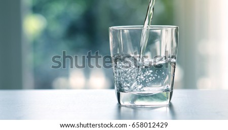 Close up pouring purified fresh drink water from the bottle on table in living room