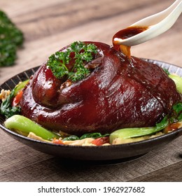 Close up of pouring savory soy sauce with spoon over Taiwanese food braised pork hock food in a plate on rustic table background. - Powered by Shutterstock