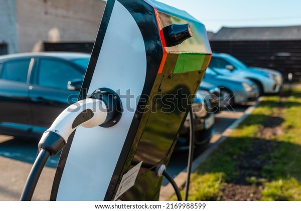 Close up power cord\
for electric car. Green station.Power supply for electric car\
battery charging.Blurred car in the background.Selective\
focus.Closeup.