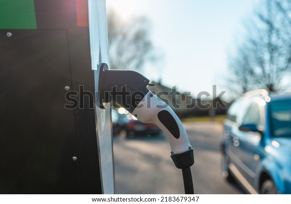 Close up power cord
for electric car. Green station.Power supply for electric car
battery charging.Blurred car in the background.Selective
focus.Closeup.
