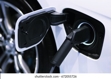 Close up of power supply plugged into an electric car being charged. - Shutterstock ID 672055726