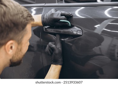 Close up to PPF installation process on a side car door. PPF is a Paint Protection Film which protect paint from scratches and stone chips. Concept of: Guard, Protect, Car, New, Work.
