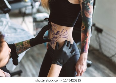 Close up prefessional tattooer in black gloves preparing do new tattoo on girl body in modern tattoo studio